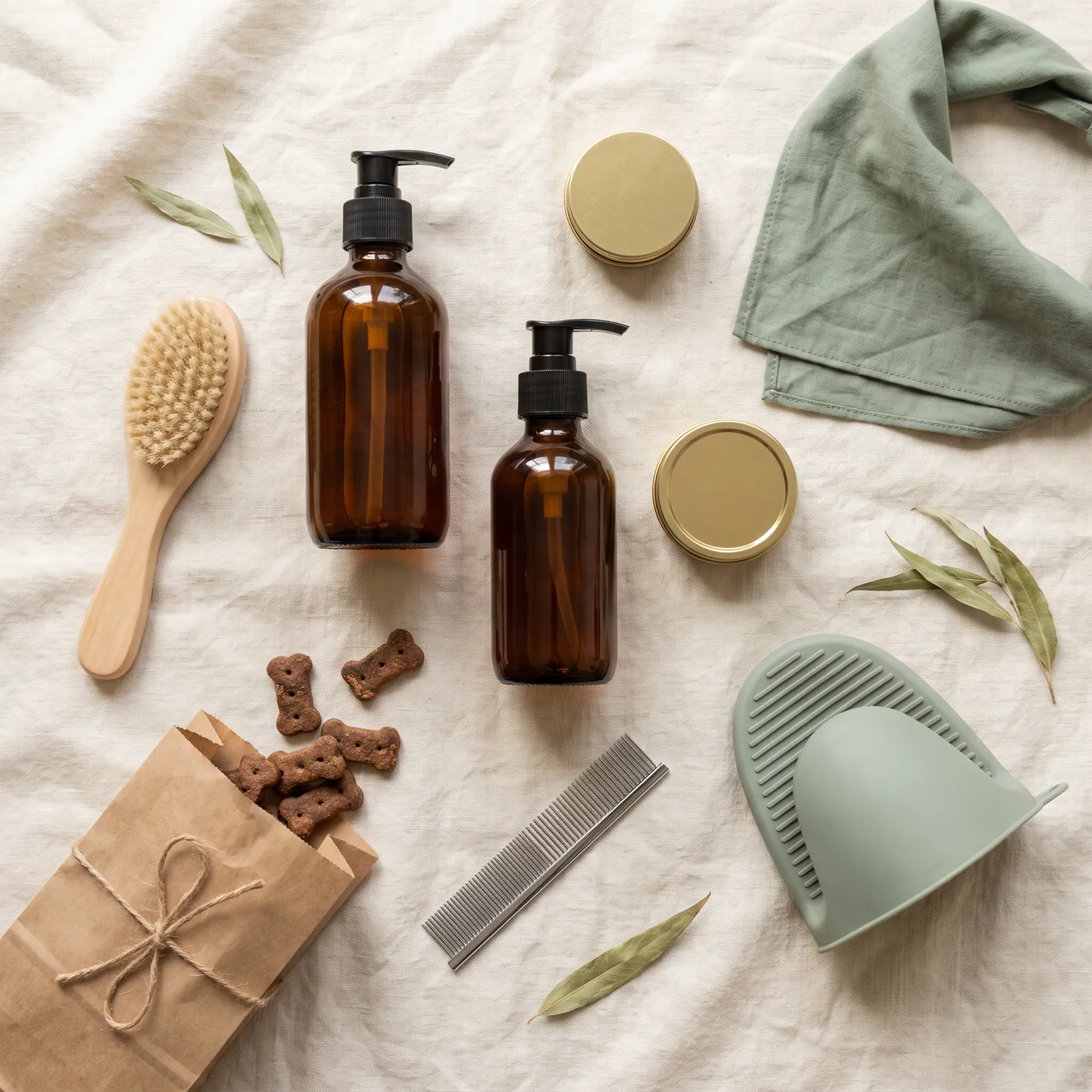 La Collection Saule à plat sur du lin : flacons ambrés sans étiquette, brosse, peigne, baume, biscuits et bandana