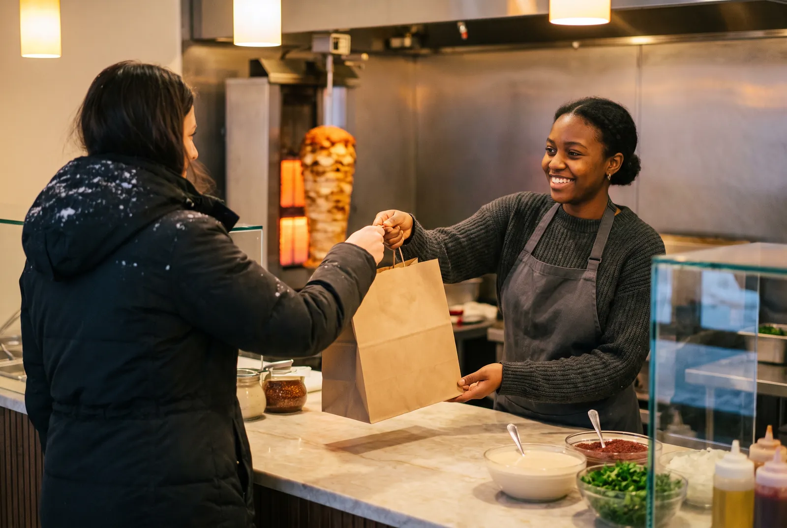 Une employée tend un sac pour emporter à une cliente en manteau d'hiver